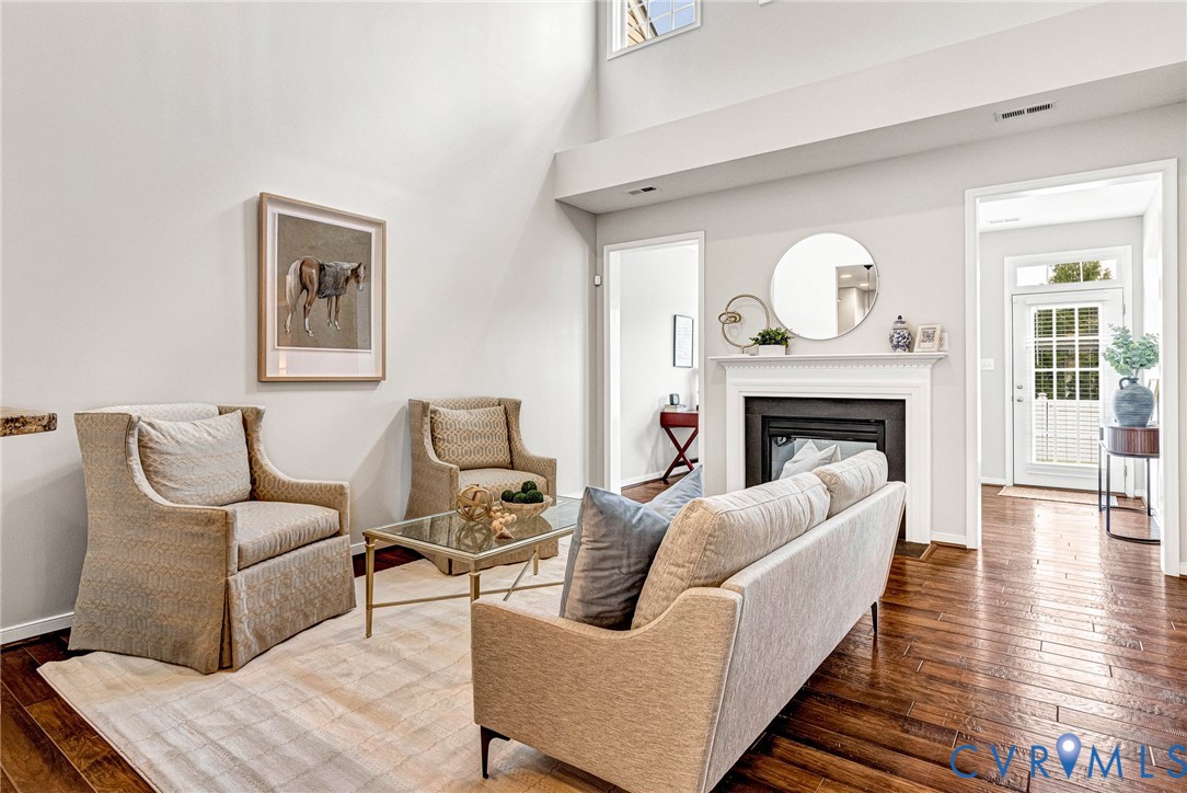 Vaulted ceilings and wood-finish flooring complement the fireplace with a white mantel and hearth