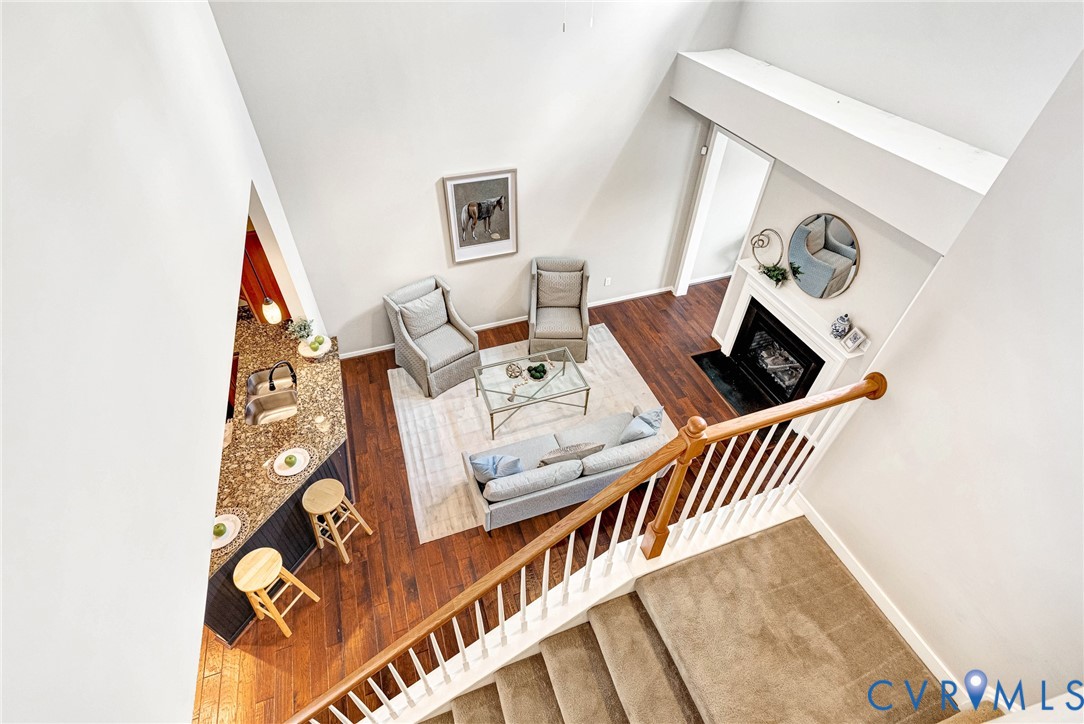 Vaulted ceilings, wood-finish flooring, staircase with wood banister, built-in fireplace, and an eat-in kitchen island with stone countertop