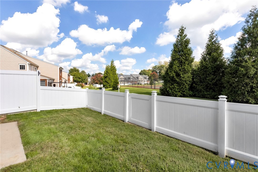 Expansive green lawn with a white privacy fence