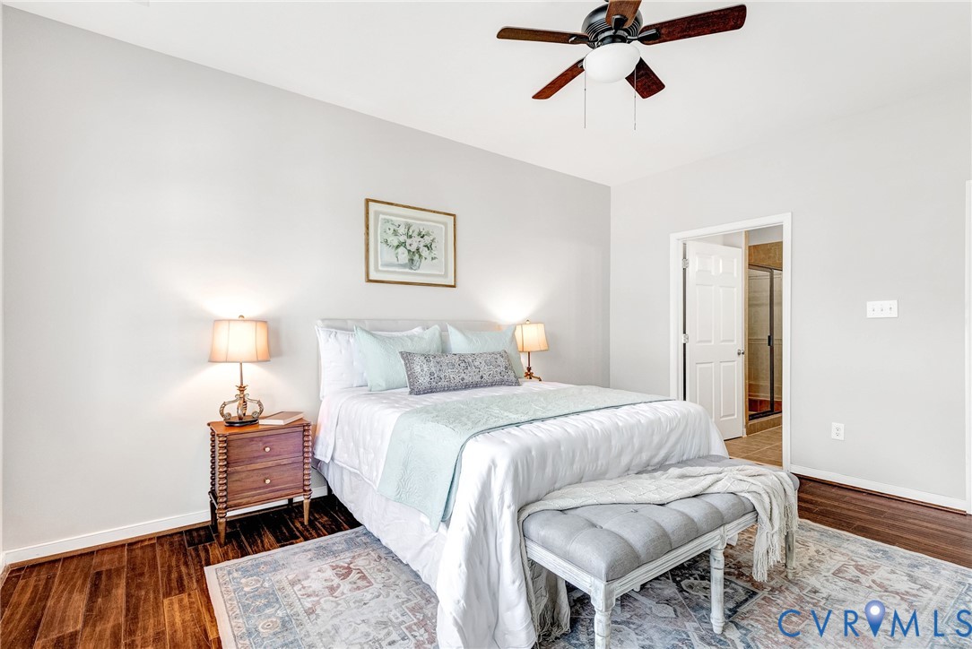 Wood-finish flooring, ceiling fan with integrated lighting, and a white interior door