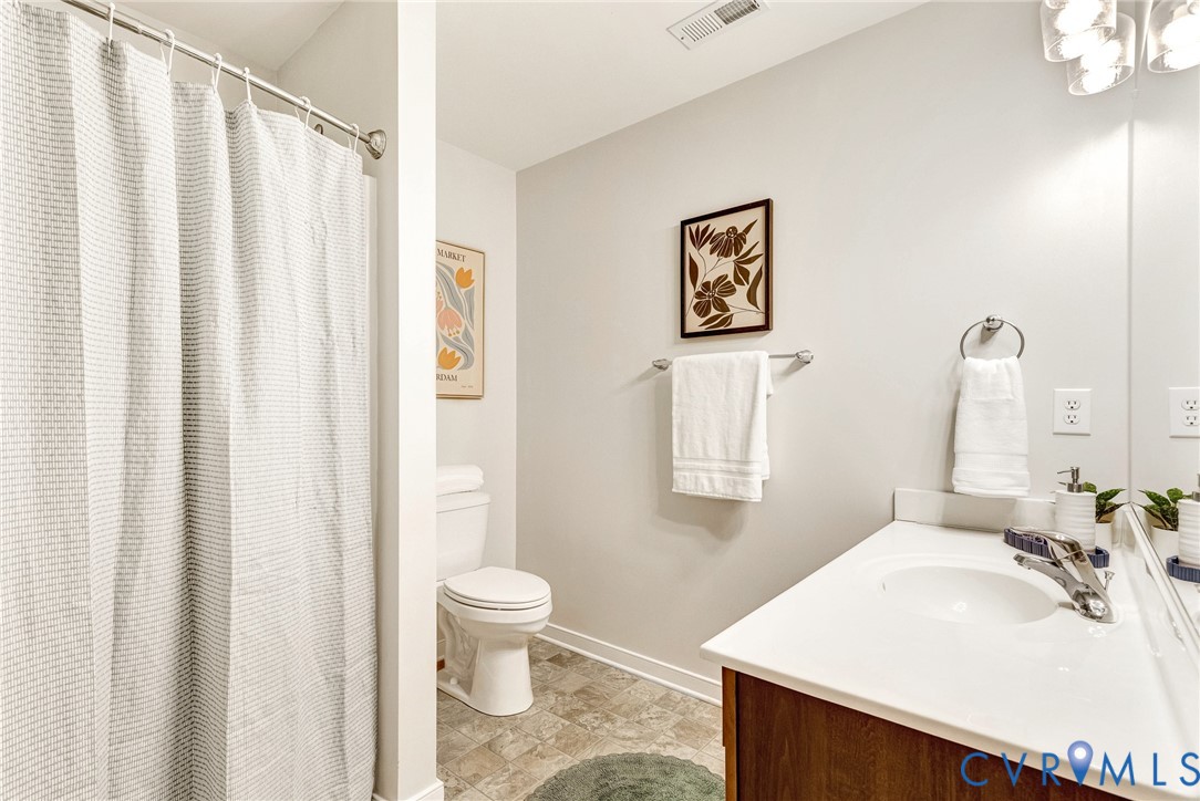 Bathroom featuring a vanity with a white countertop, undermount sink, and wood-finish cabinetry
