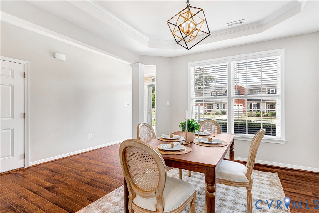 Tray ceiling with crown molding, wood-finish flooring, and a contemporary geometric chandelier Tray ceiling with crown molding, wood-finish flooring, and a contemporary geometric chandelier