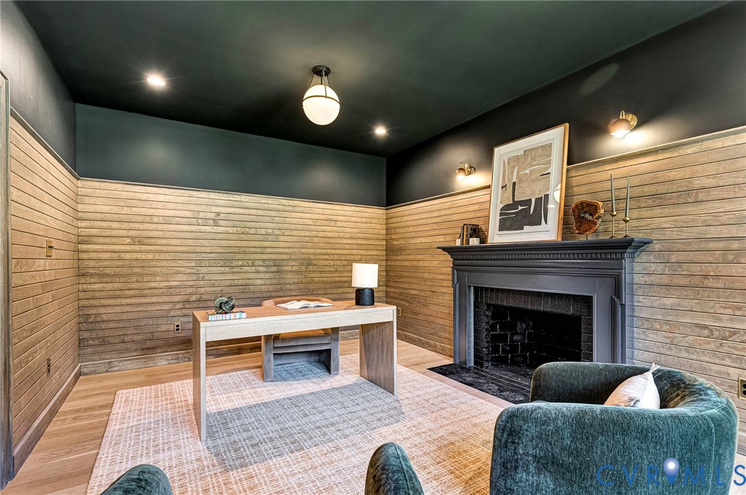 Horizontal wood plank wall paneling, painted fireplace surround with brick insert, recessed lighting, and wall-mounted light fixtures