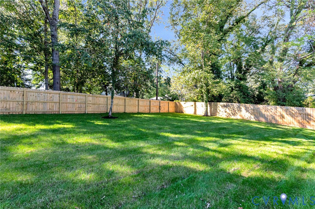Fenced backyard featuring a manicured lawn and mature trees
