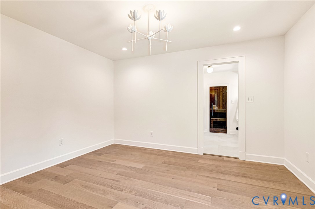 Wood-finish flooring, multi-arm floral-inspired chandelier, recessed ceiling lighting, and crisp white wall finishes