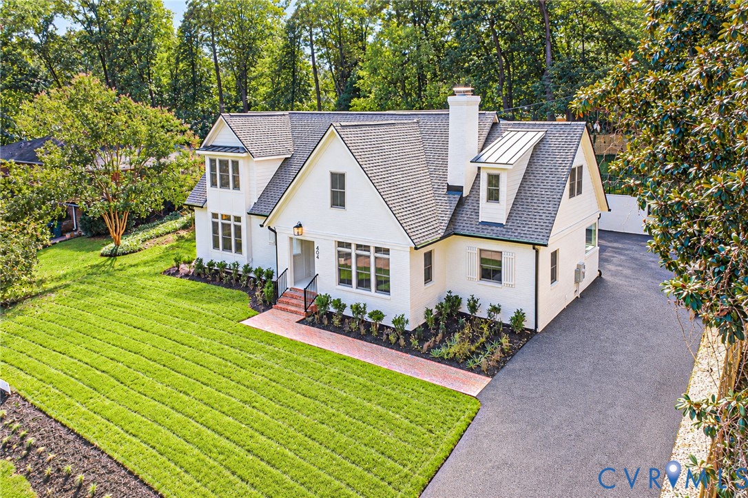 Multi-gabled exterior featuring white painted masonry, an asphalt shingle roof, a red brick walkway, and an expansive paved driveway Multi-gabled exterior featuring white painted masonry, an asphalt shingle roof, a red brick walkway, and an expansive paved driveway