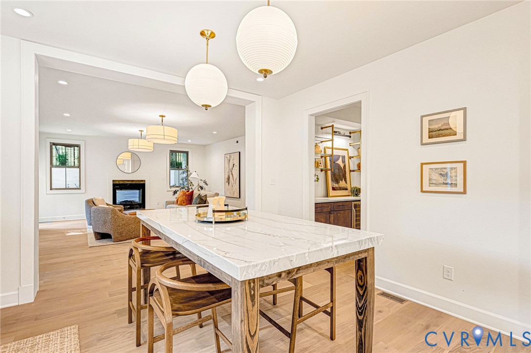 Light-toned wood-finish flooring, stone-surfaced island, and globe-style pendant lighting