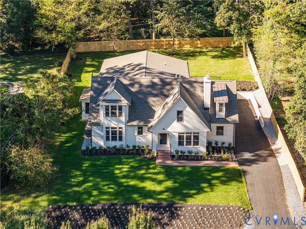 Custom-built residence featuring a white exterior, steep gable roofline, exterior brick walkway, asphalt driveway, and enclosed perimeter fencing