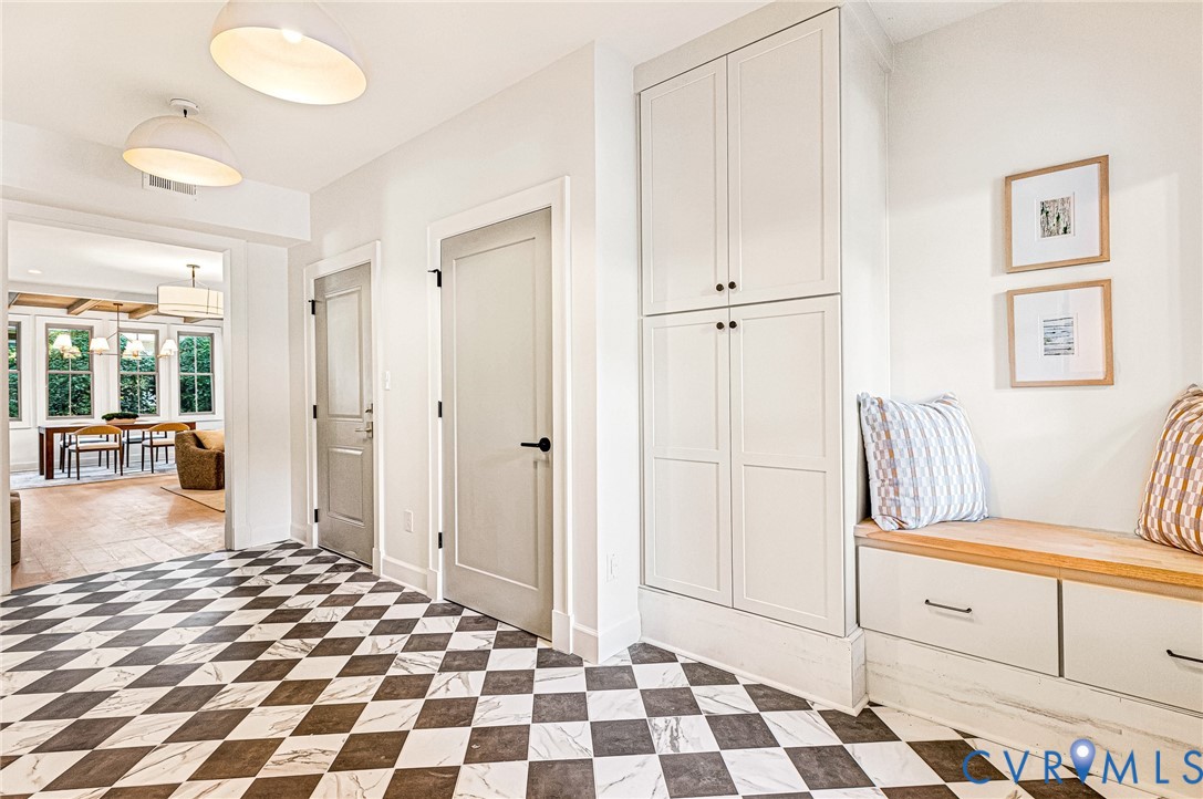 Checkerboard stone tile flooring, built-in floor-to-ceiling cabinetry, custom wooden bench seat with lower storage drawers, and dual dome-style pendant lighting