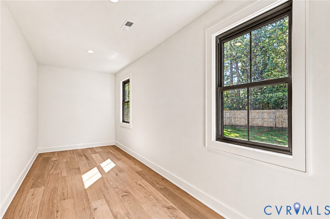 Interior space featuring wood-finish flooring, recessed lighting, and dark-framed windows with exterior trim