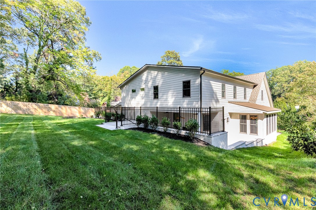 Exterior view featuring horizontal siding, a fenced concrete patio, an enclosed sunroom, and manicured landscaping