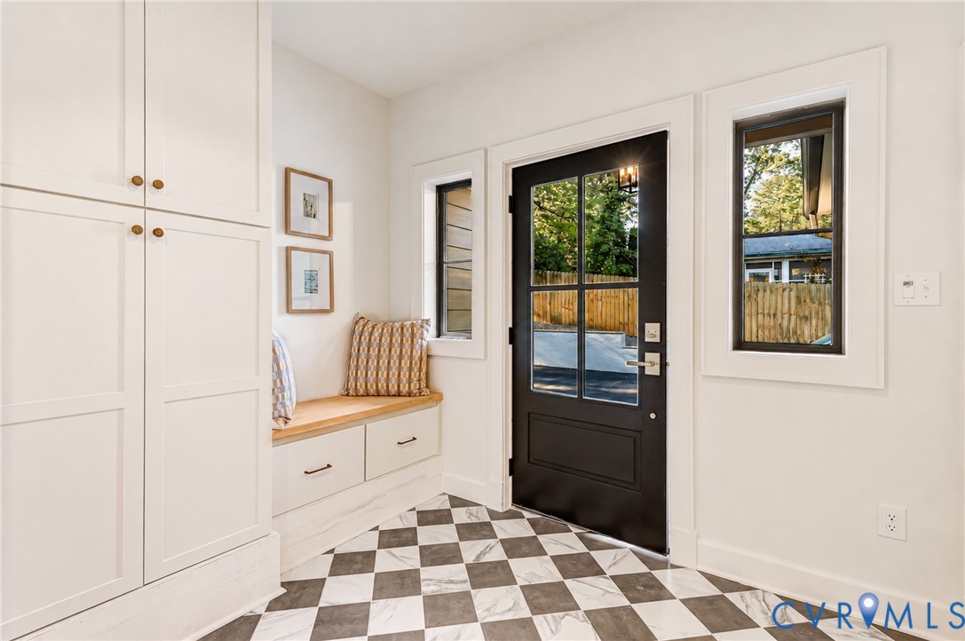 Entryway featuring checkerboard tile flooring, built-in floor-to-ceiling cabinetry, a custom bench with storage drawers, and a multi-pane door with black hardware
