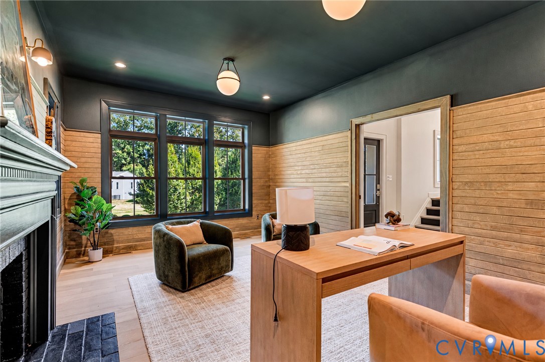Custom room featuring horizontal wood-plank wall treatment, expansive multi-pane windows, wood-finish flooring, a brick fireplace surround, and recessed and globe-style lighting