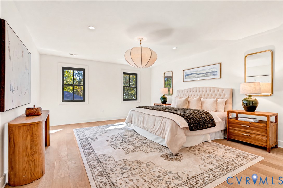Light-filled room featuring wood-finish flooring, recessed lighting, a modern pendant light fixture, and black-framed windows
