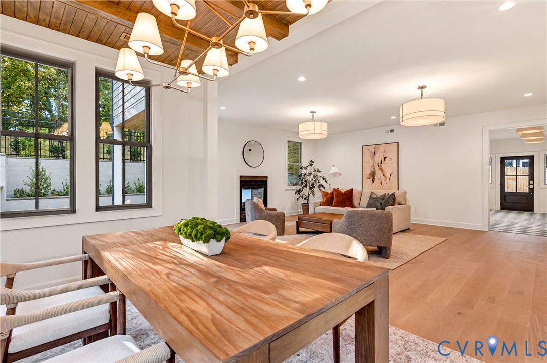 Wood-plank ceiling treatment, multi-light chandelier, wide-plank wood-finish flooring, and recessed lighting