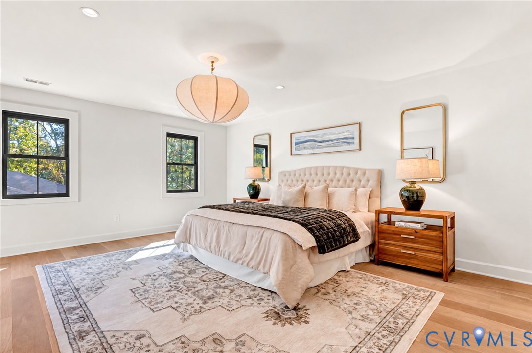 Neutral interior with wood-finish flooring, recessed lighting, architectural pendant fixture, and high-contrast window casing