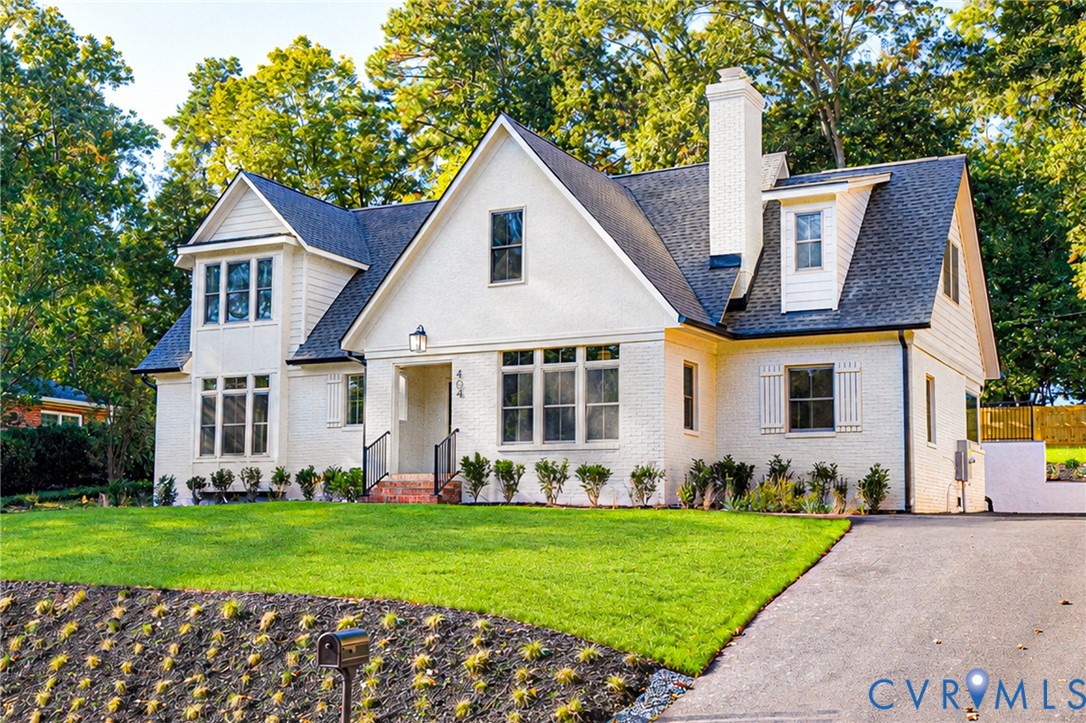 Traditional brick exterior featuring a steep-pitched roofline, multi-pane windows, a central chimney, and an asphalt driveway Traditional brick exterior featuring a steep-pitched roofline, multi-pane windows, a central chimney, and an asphalt driveway