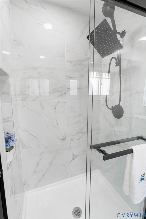 Glass-enclosed shower with white tiled walls and a rain shower head