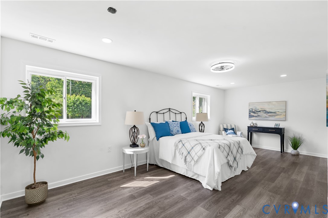 Recessed lighting, wood-finish flooring, white walls, multiple windows, and a ceiling-mounted light fixture
