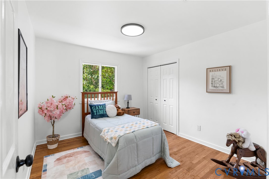 Bright room featuring wood-finish flooring, a double-door closet, and white walls