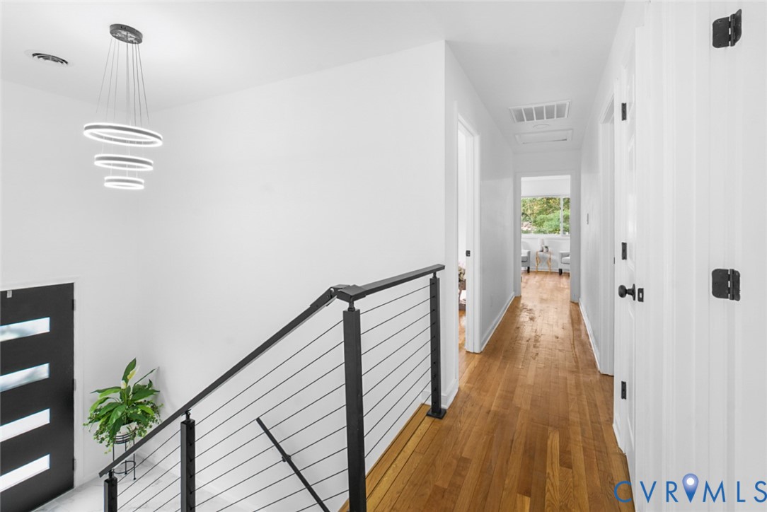 Modern tiered chandelier, engineered wood flooring, contemporary cable railing, crisp white walls, and black hardware Modern tiered chandelier, engineered wood flooring, contemporary cable railing, crisp white walls, and black hardware