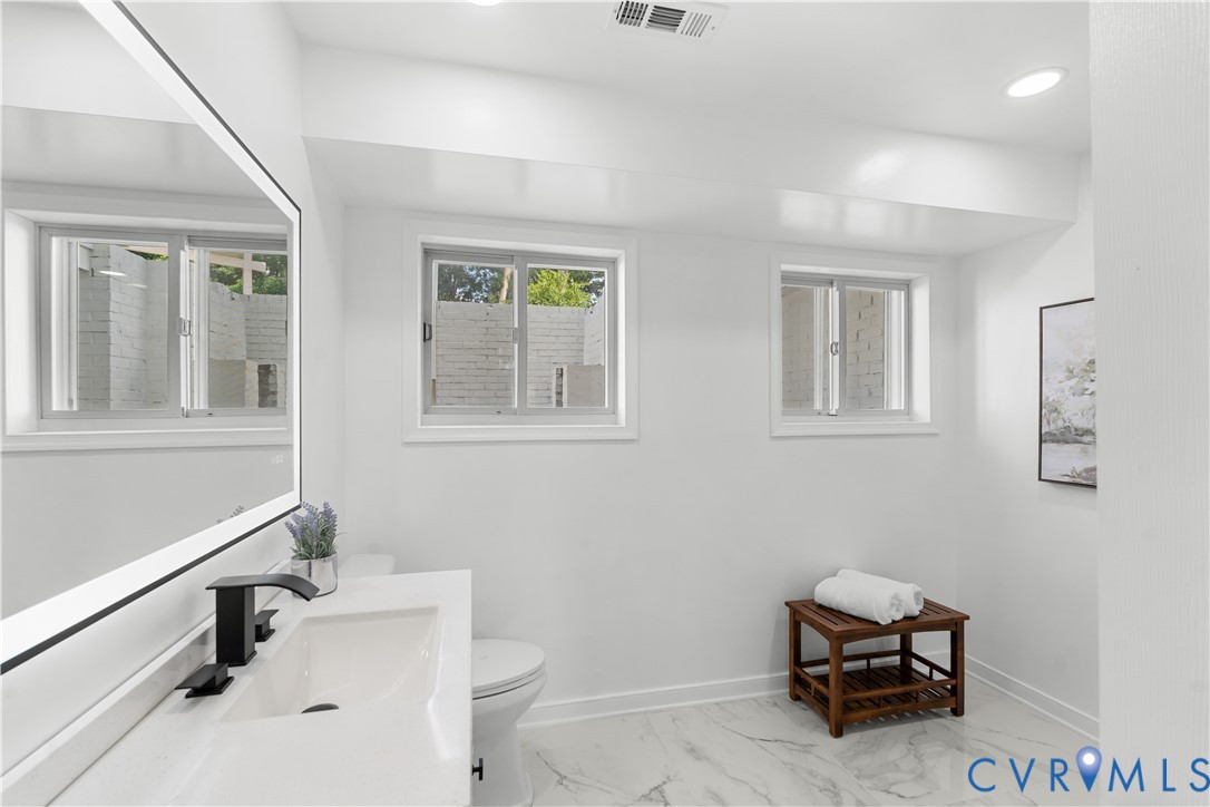 Bathroom featuring a floating vanity with a vessel sink, black faucet, illuminated mirror, recessed lighting, and white-patterned flooring