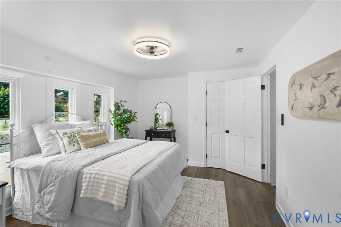 Wood-finish flooring, white paneled doors, ceiling-mounted light fixture, white walls, and multiple windows