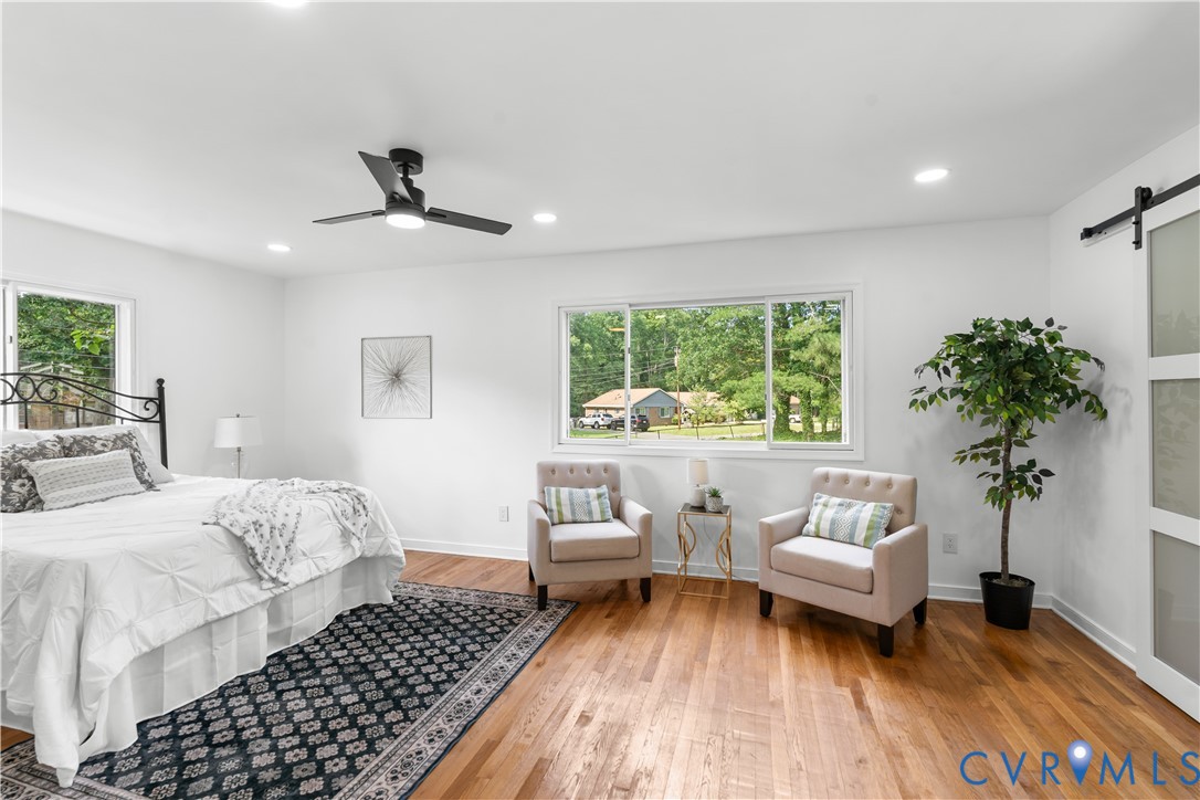 Recessed lighting, wood-finish flooring, multiple windows, ceiling fan, and barn door entry Recessed lighting, wood-finish flooring, multiple windows, ceiling fan, and barn door entry