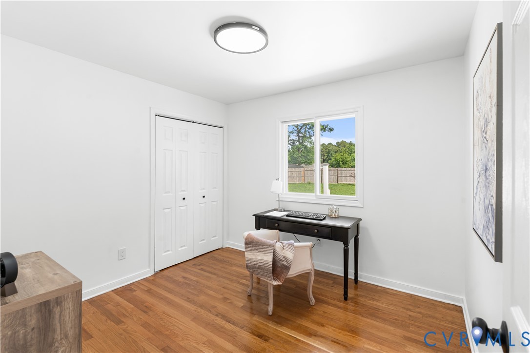 Hardwood flooring, white walls, recessed lighting, double bi-fold closet, and a window with exterior views