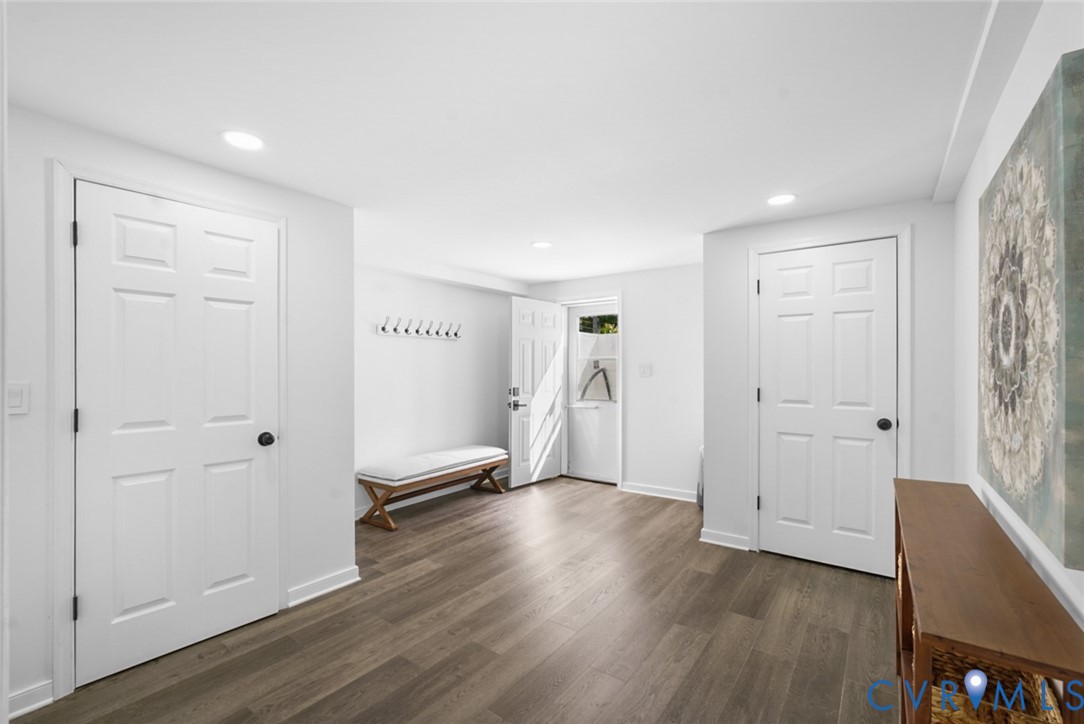 Wood-finish flooring, recessed lighting, white panel doors, and a built-in coat rack