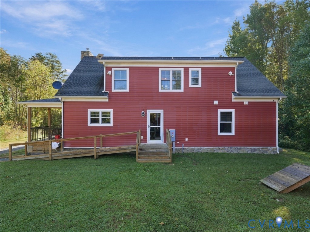 Two-story exterior featuring red horizontal siding, a stone veneer foundation, a multi-gabled shingle roof, and an attached wooden ramp