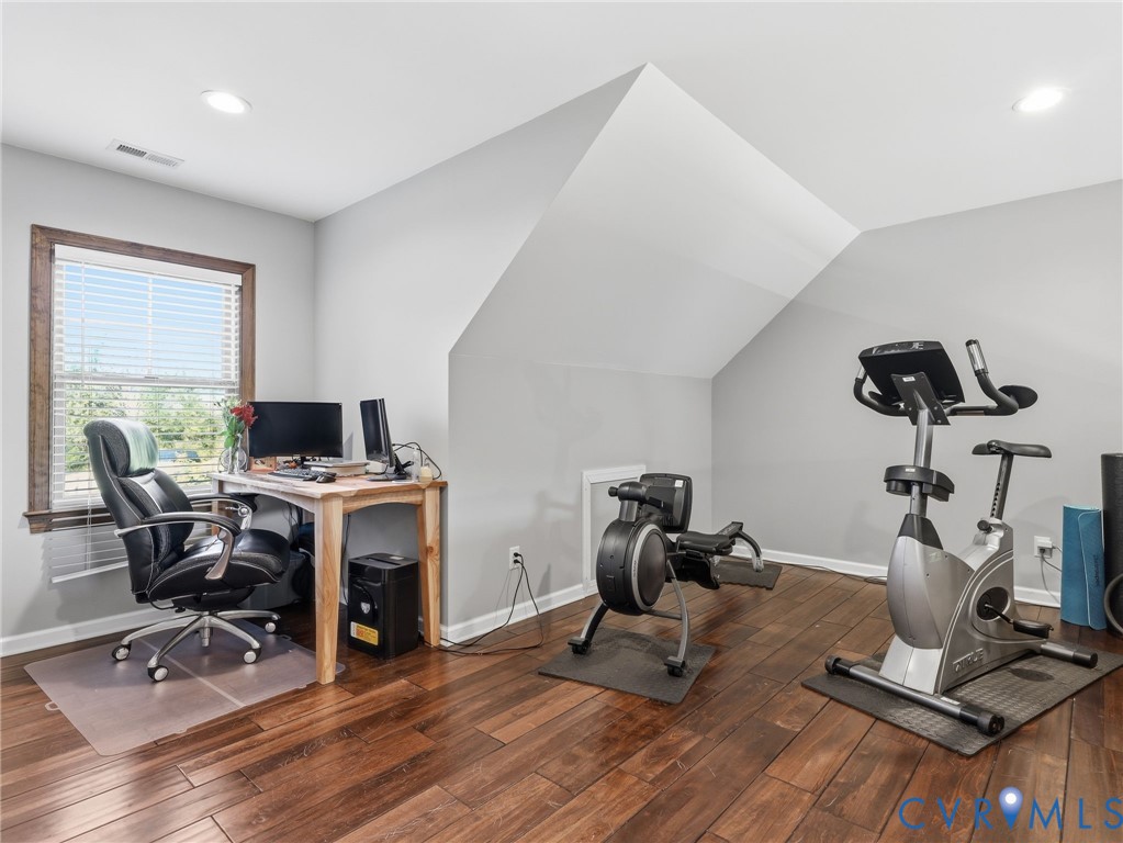 Wood-finish flooring, recessed lighting, and a window with dark wood trim in a room featuring vaulted ceilings