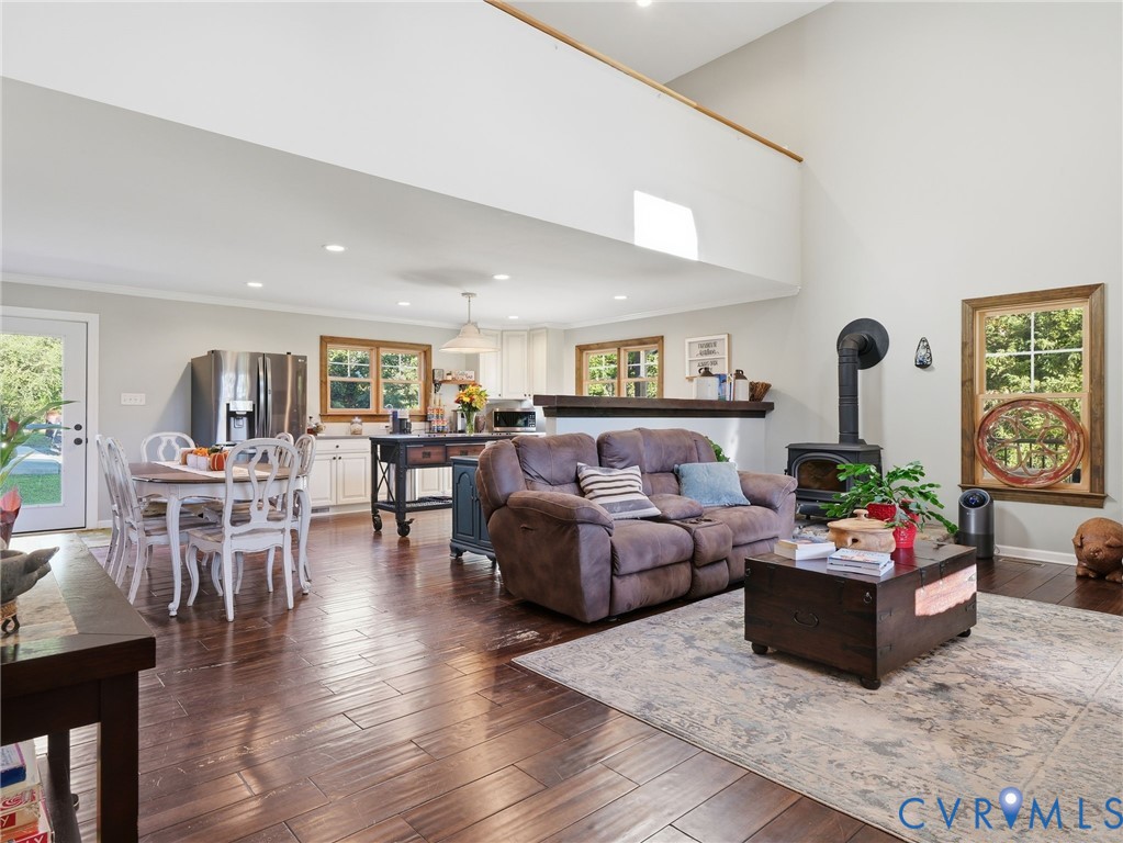 Vaulted ceilings, dark wood-finish flooring, recessed lighting, and a cast-iron wood-burning stove with a chimney pipe Vaulted ceilings, dark wood-finish flooring, recessed lighting, and a cast-iron wood-burning stove with a chimney pipe