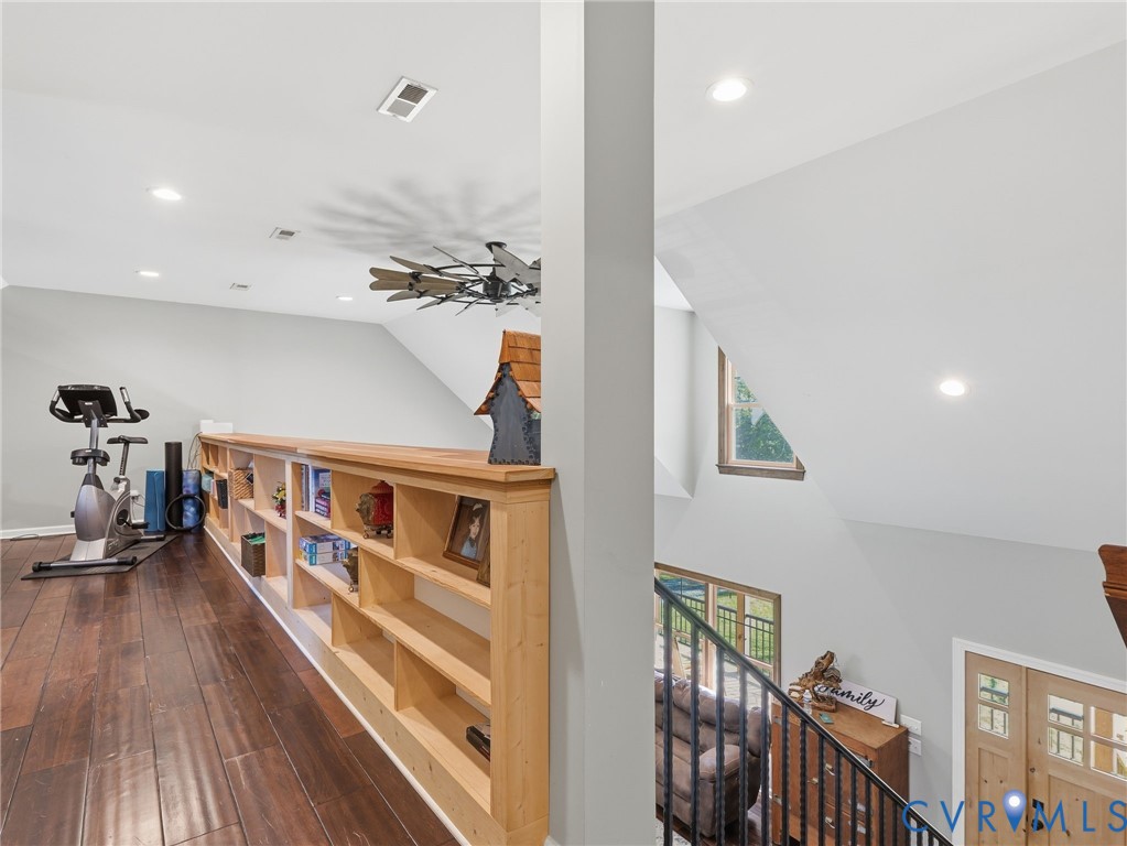 Upper level featuring wood-finish flooring, custom built-in wood shelving, recessed lighting, and a decorative industrial-style ceiling fan