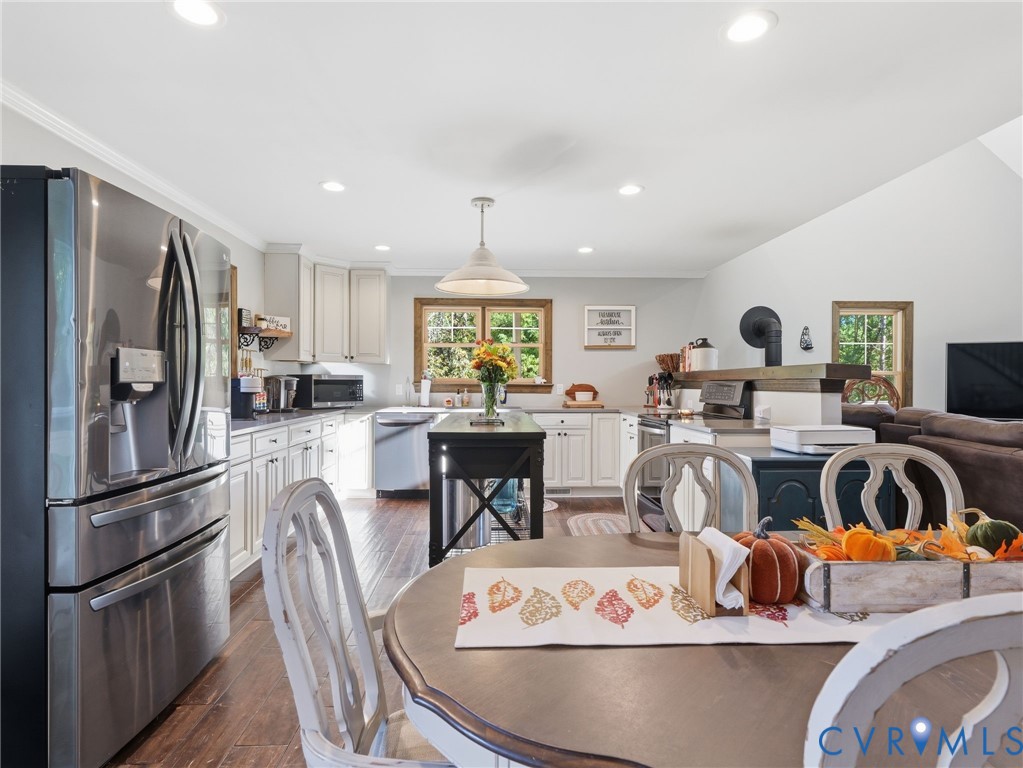 Kitchen featuring wood-finish flooring, white cabinetry, stainless steel appliances, a center island with a dark finish, and recessed ceiling lighting