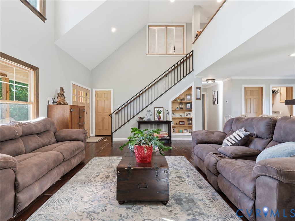 Vaulted ceilings, wood-finish flooring, metal staircase railing, built-in recessed shelving, and large windows with natural wood trim