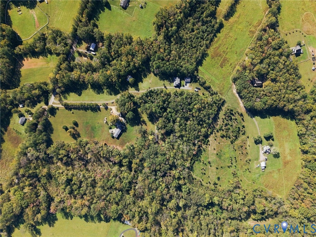 Aerial perspective of expansive acreage featuring mature woodland, open grassy fields, and private winding access roads