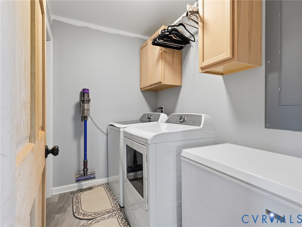 Utility area featuring wood-finish flooring, shaker-style light wood cabinetry, and a mounted metal clothing rod