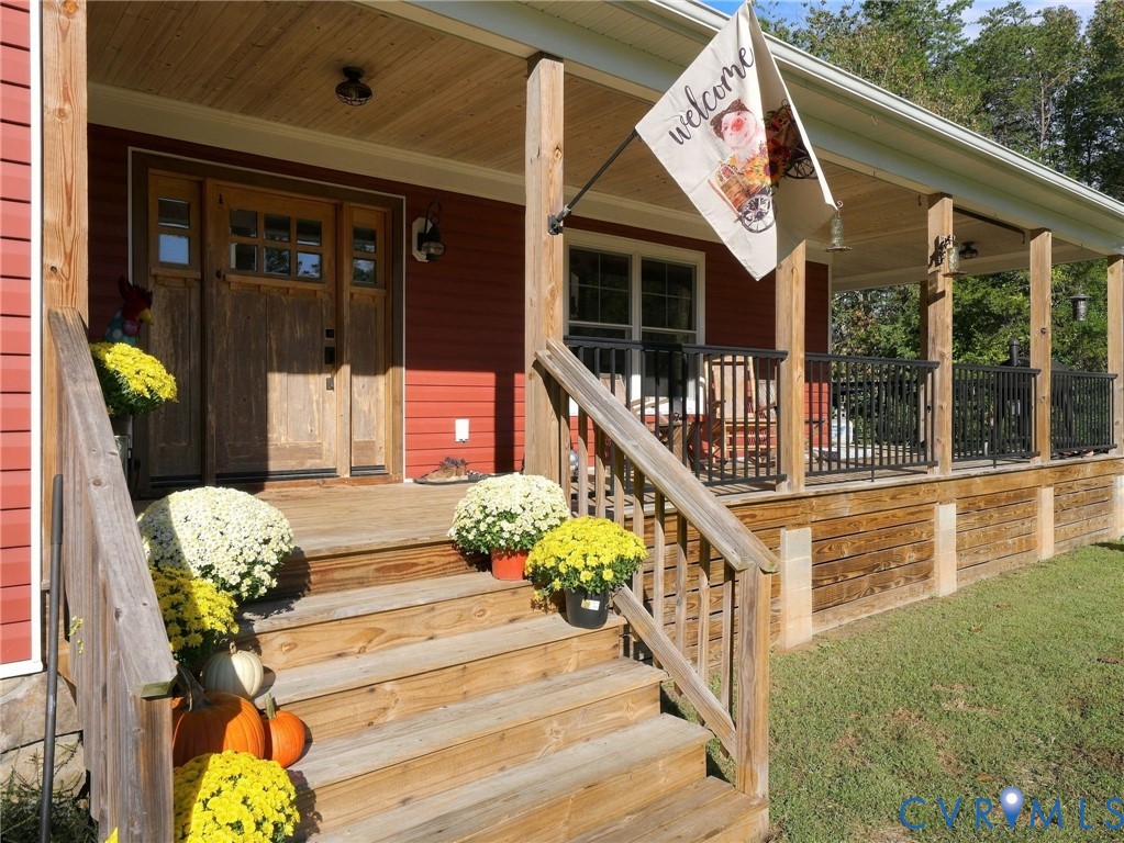 Covered wooden front porch featuring horizontal lap siding, a wood-paneled ceiling, black metal railing, and a wood-frame entry door with multi-pane glass inserts Covered wooden front porch featuring horizontal lap siding, a wood-paneled ceiling, black metal railing, and a wood-frame entry door with multi-pane glass inserts