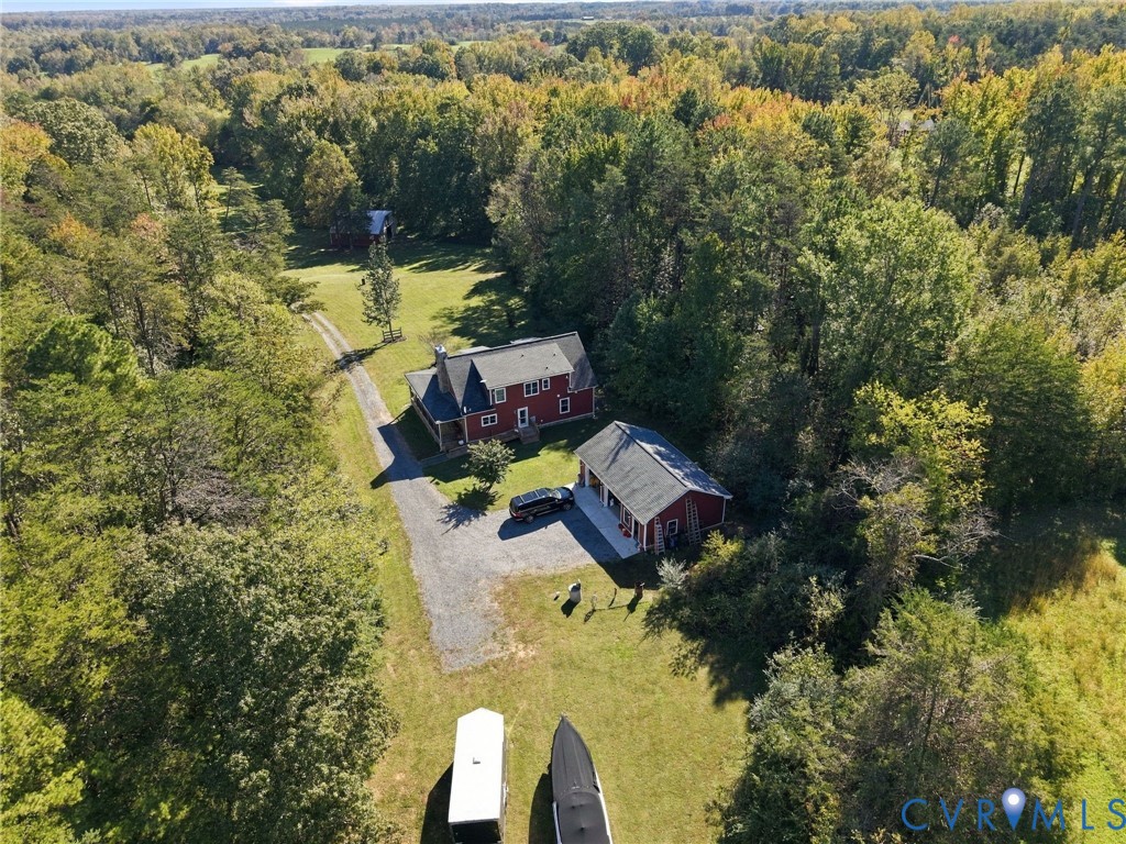 Expansive wooded acreage featuring a two-story residence, a detached garage with multiple bays, and an extensive gravel driveway