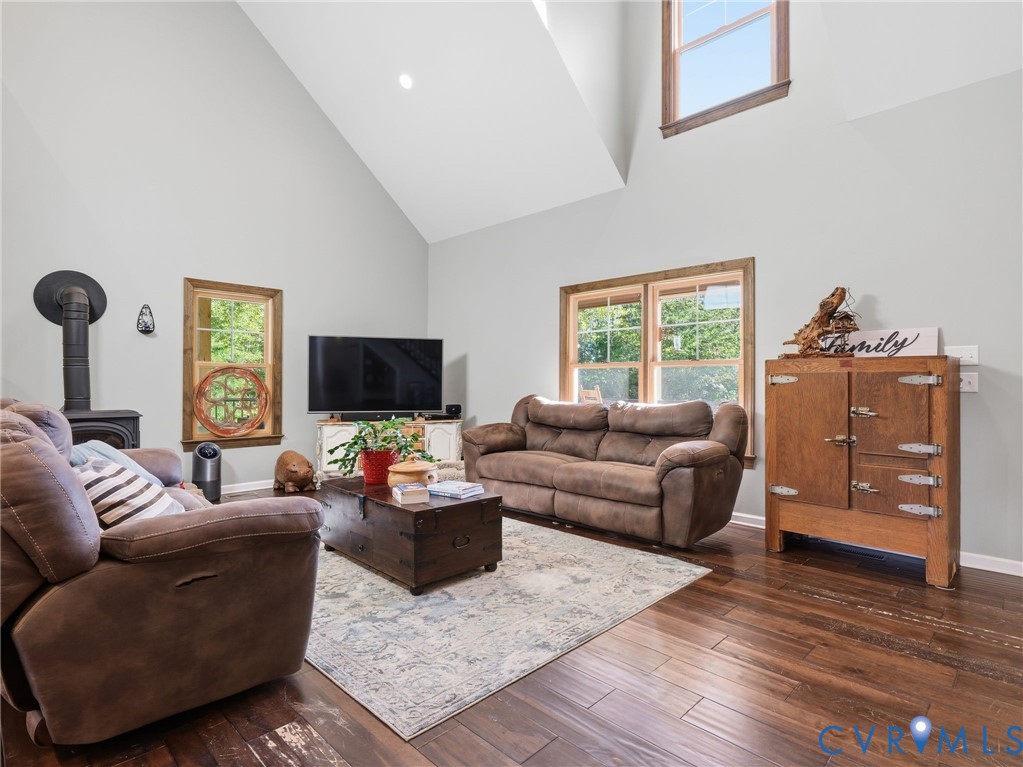 Vaulted ceilings, wood-finish flooring, multi-pane windows with natural wood trim, and a cast-iron wood stove