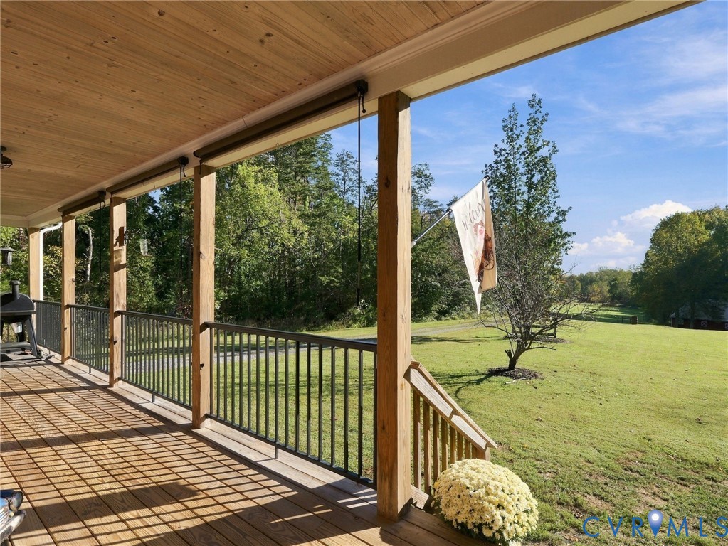 Covered porch featuring natural wood-finish decking, exposed wood plank ceiling, and metal railing Covered porch featuring natural wood-finish decking, exposed wood plank ceiling, and metal railing
