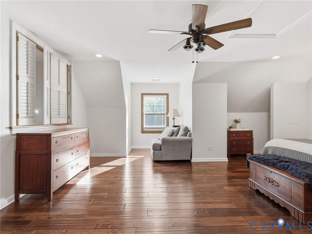 Wood-finish flooring, vaulted ceilings, multi-blade ceiling fan with integrated lighting, recessed lighting, and windows with interior shutters