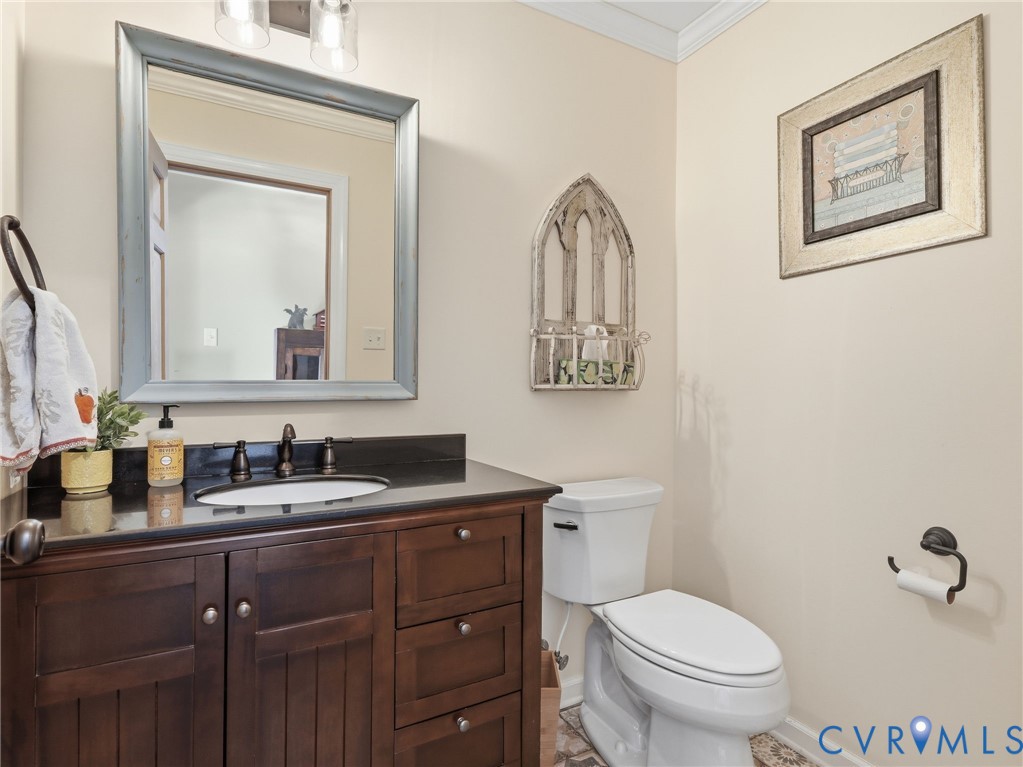 Dark-stained wood vanity featuring a stone countertop, an undermount sink with a widespread oil-rubbed bronze faucet, and a dual-light wall sconce