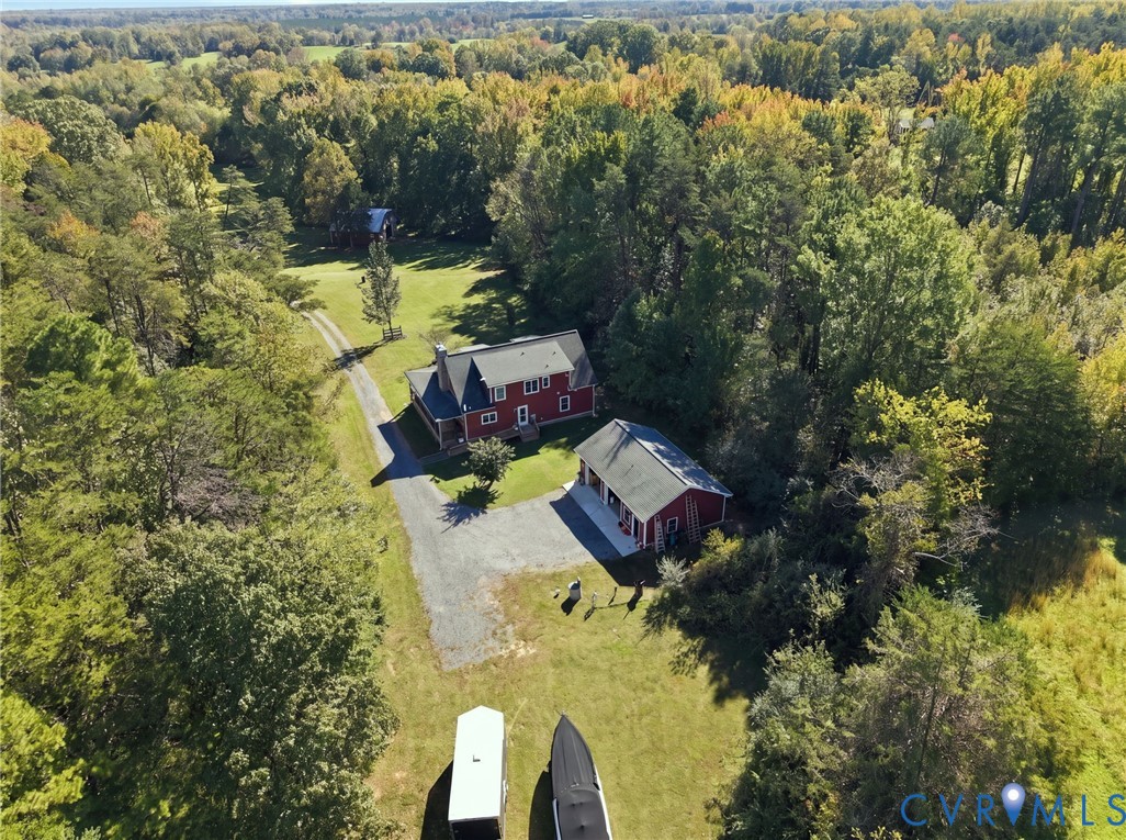 Expansive rural property featuring a multi-story residence, a detached garage structure, a gravel driveway, and mature perimeter woodland Expansive rural property featuring a multi-story residence, a detached garage structure, a gravel driveway, and mature perimeter woodland