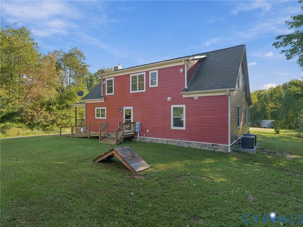 Red siding exterior featuring a stone foundation, asphalt shingle roof, wood deck with stairs, and multiple multi-pane windows