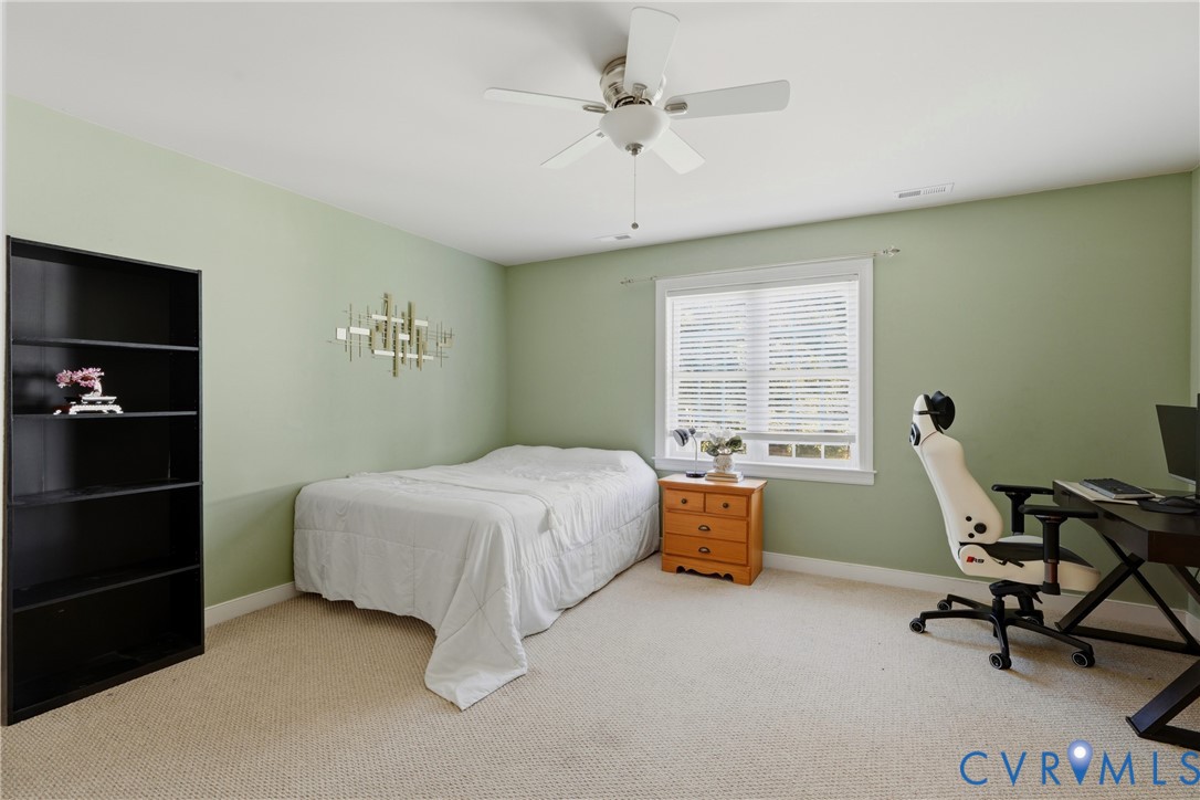Room featuring neutral carpeting, a central ceiling fan with integrated lighting, and a window with horizontal blinds