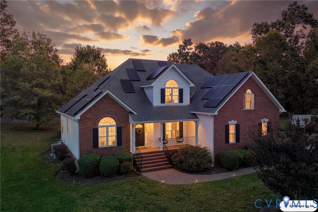 Two-story brick and siding exterior featuring roof-mounted solar panels, arched windows, an elevated front porch with railing, and a concrete walkway