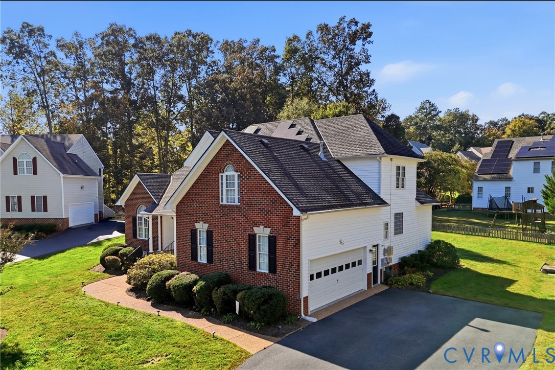 Multi-level exterior featuring a brick and siding facade, an attached two-car garage, asphalt shingle roofing, and a paved driveway