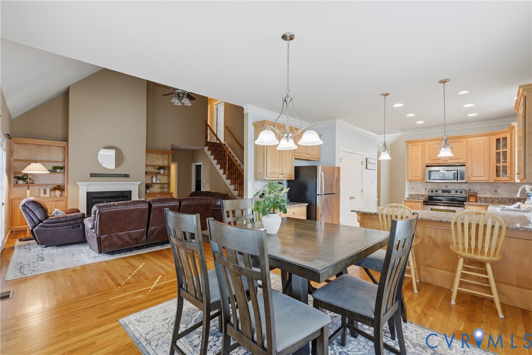Vaulted ceilings, wood-finish flooring, fireplace with custom built-in shelving, wooden cabinetry, and recessed lighting